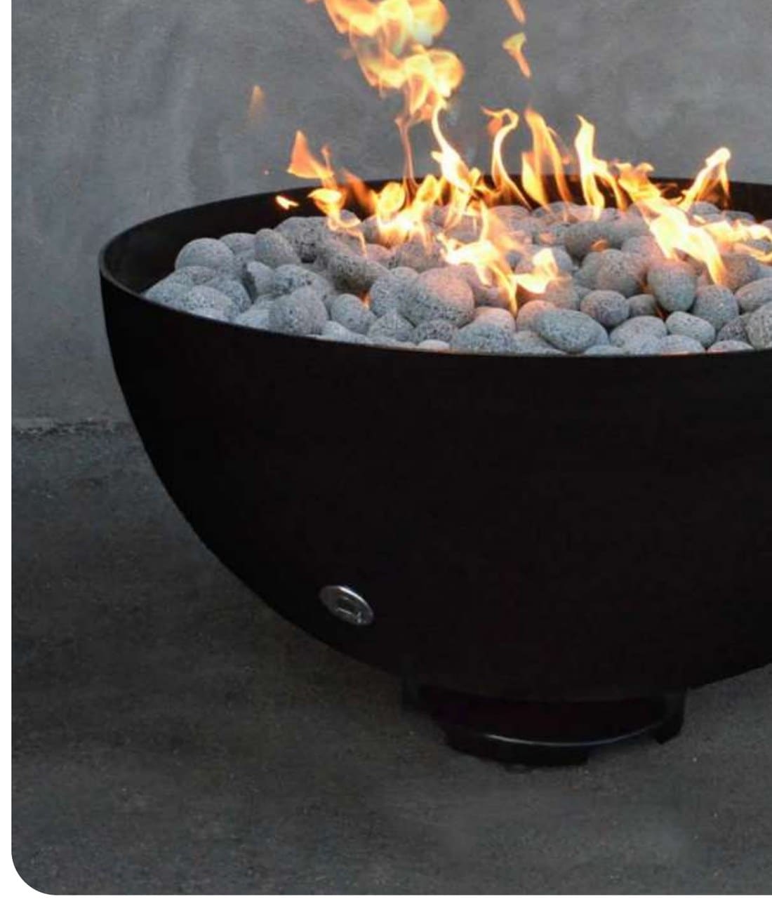Ember round gas fire bowl in black metallic finish, filled with lava pebbles and lit