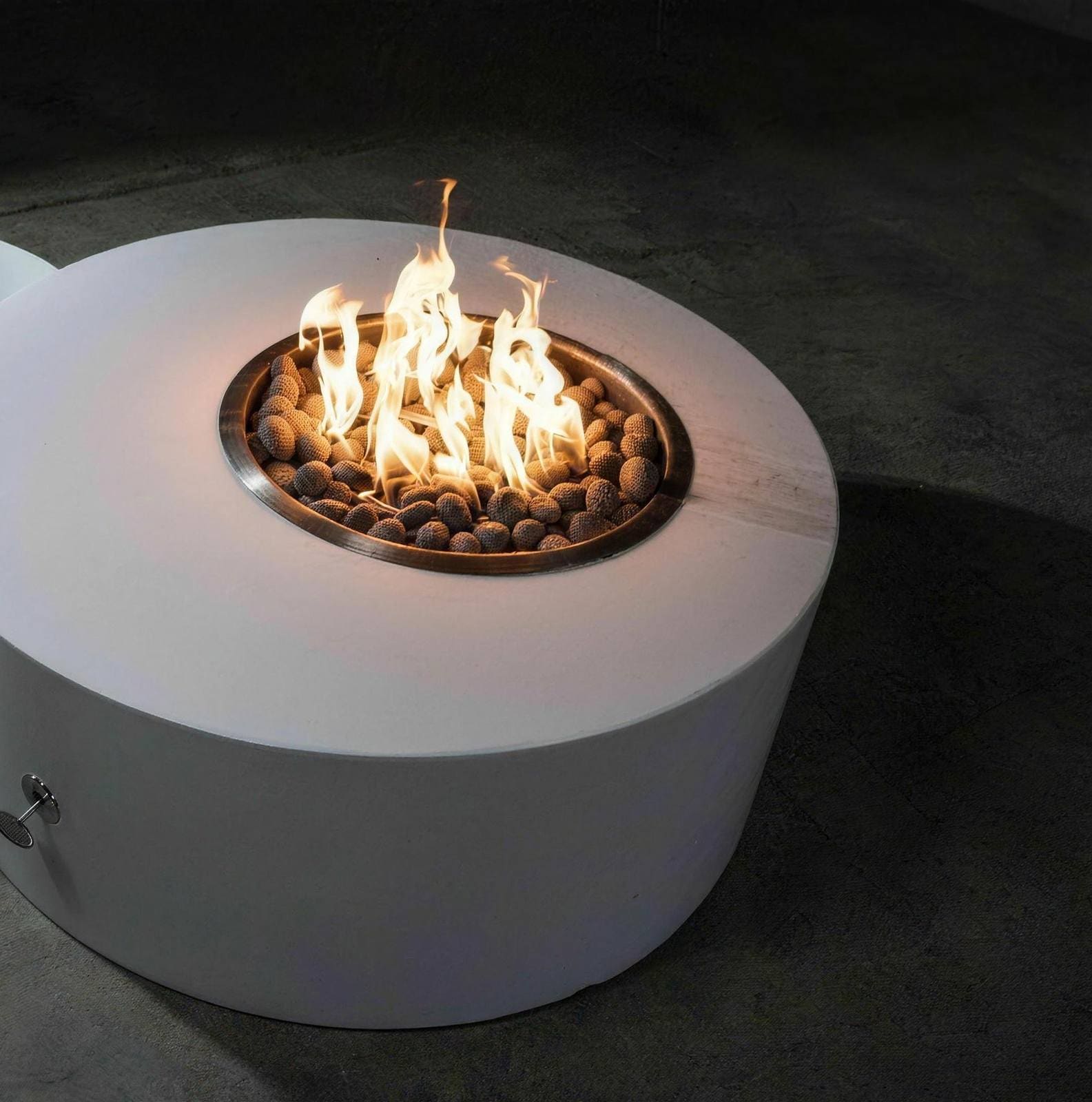 Illina round gas fire table in white matte concrete with a copper burner and lava rock